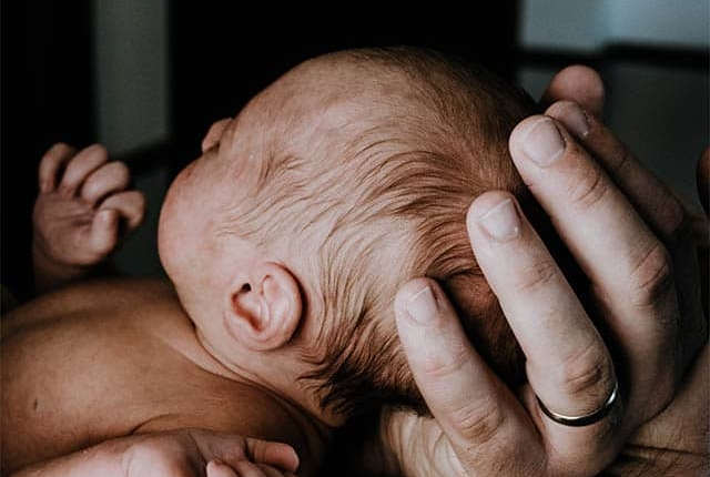 Close up of a father's hand holding a newborn baby